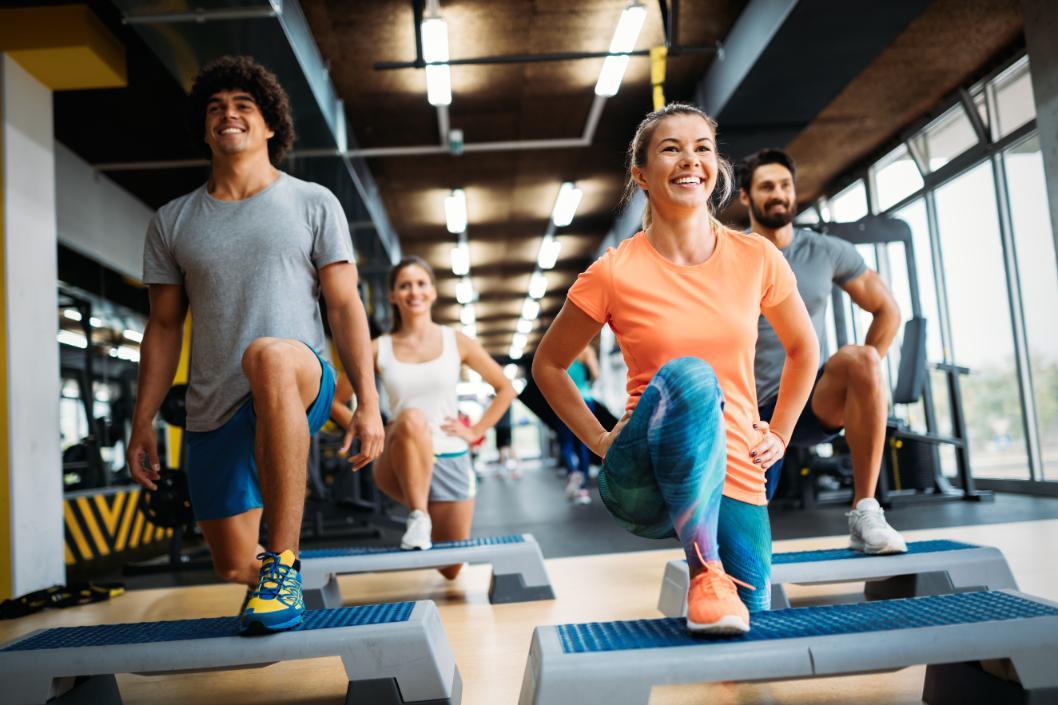 Cours collectif femmes et hommes en train de réaliser des exercices sur stepper.