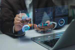 Homme d’affaires utilisant un stylet pour interagir avec des graphiques de données et des statistiques numériques affichés en réalité augmentée au-dessus d’un ordinateur portable, illustrant l’analyse de données et la visualisation interactive.